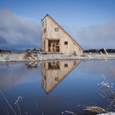 Casa Lenga exterior reflected in lagoon at dusk, Puerto Natales